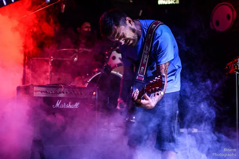 Guitarrista entre humo rosa y rojo frente a un amplificador Marshall en Entriopia Fest
