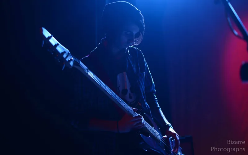 Nahuel Tindalos en silueta con la guitarra, bajo luz azul y roja en La Experimental