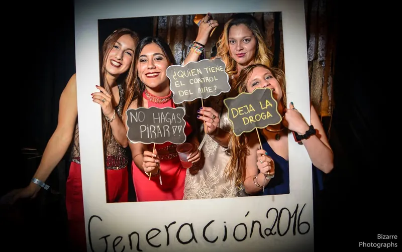 Tres chicas posando en un marco de foto de “Generación 2016” en una graduación